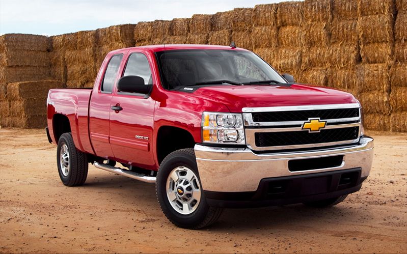 Red Chevrolet Silverado parked by hay bales