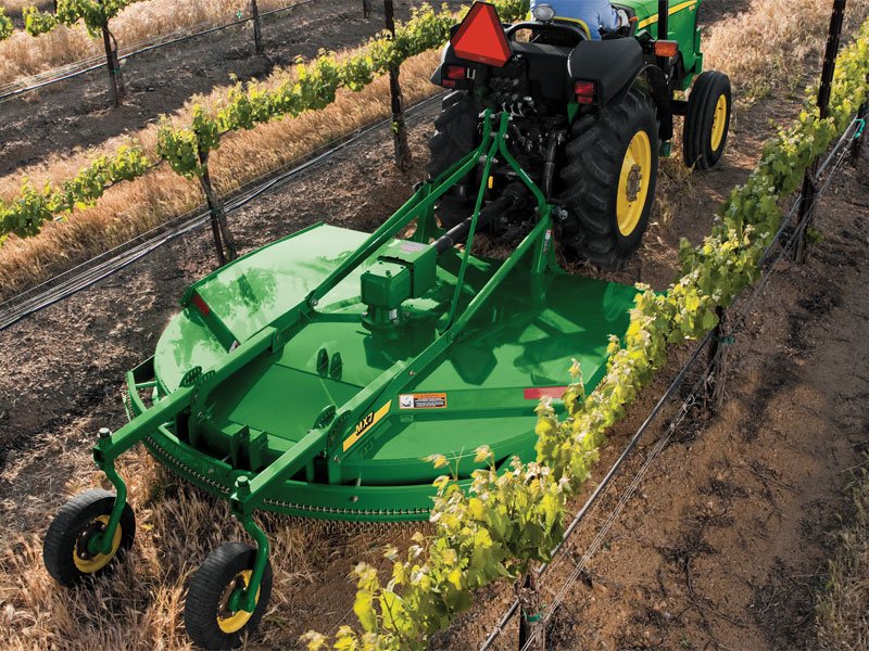 Tractor pulling a rotary mower attachment