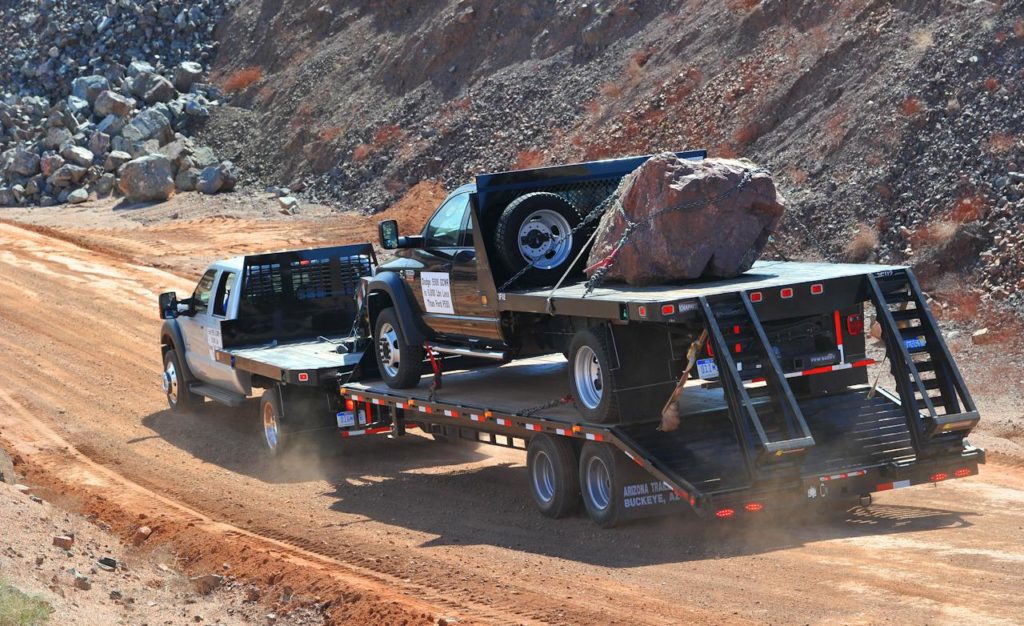 Summit truck and trailer hauling a large boulder on a mountain road